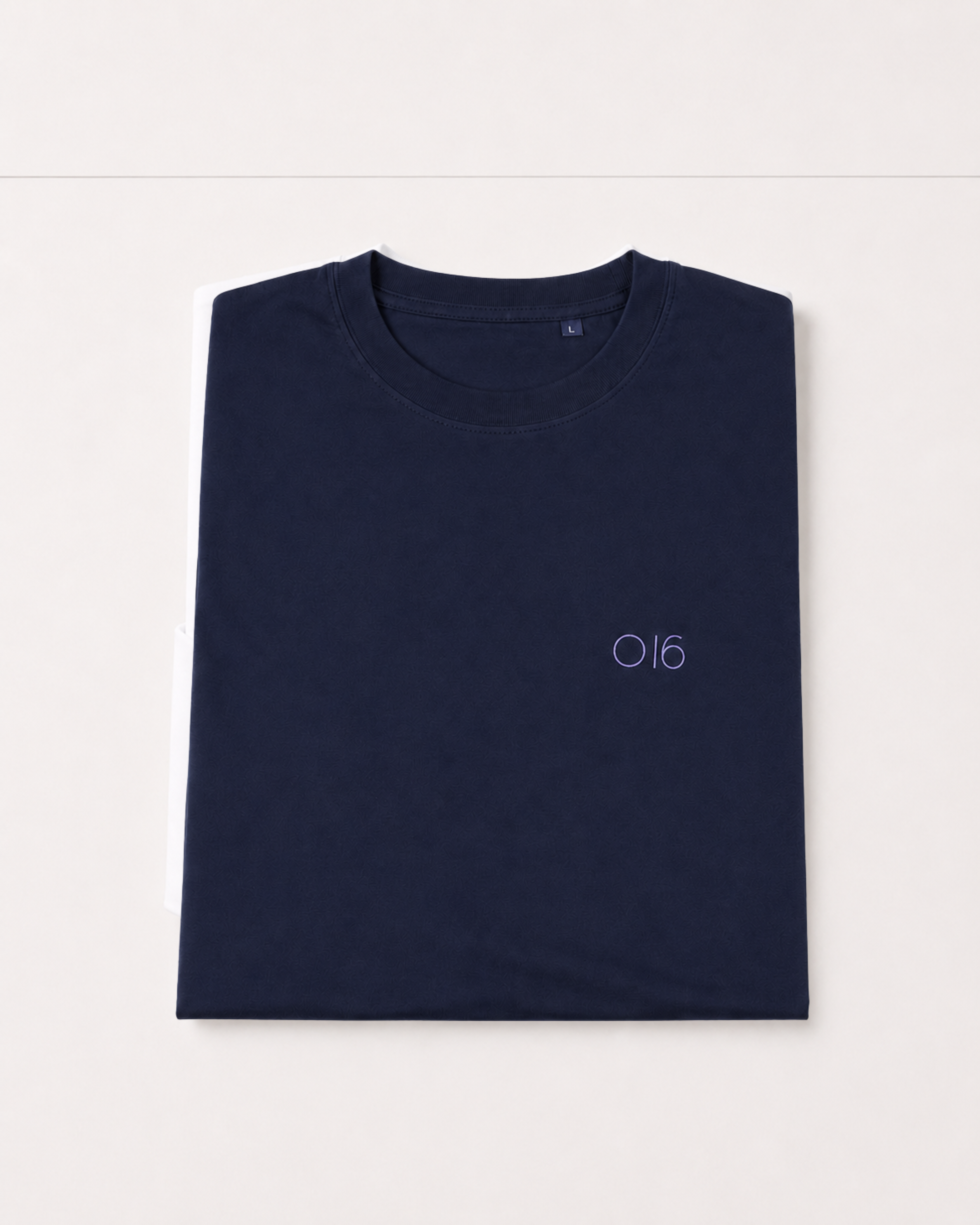 Studio: Sammenfoldet navy O16 t-shirt i økologisk bomuld med broderet O16-logo, størrelse L, studieshot på hvid | Folded navy O16 organic cotton t-shirt with embroidered O16 logo, size L, studio shot on white