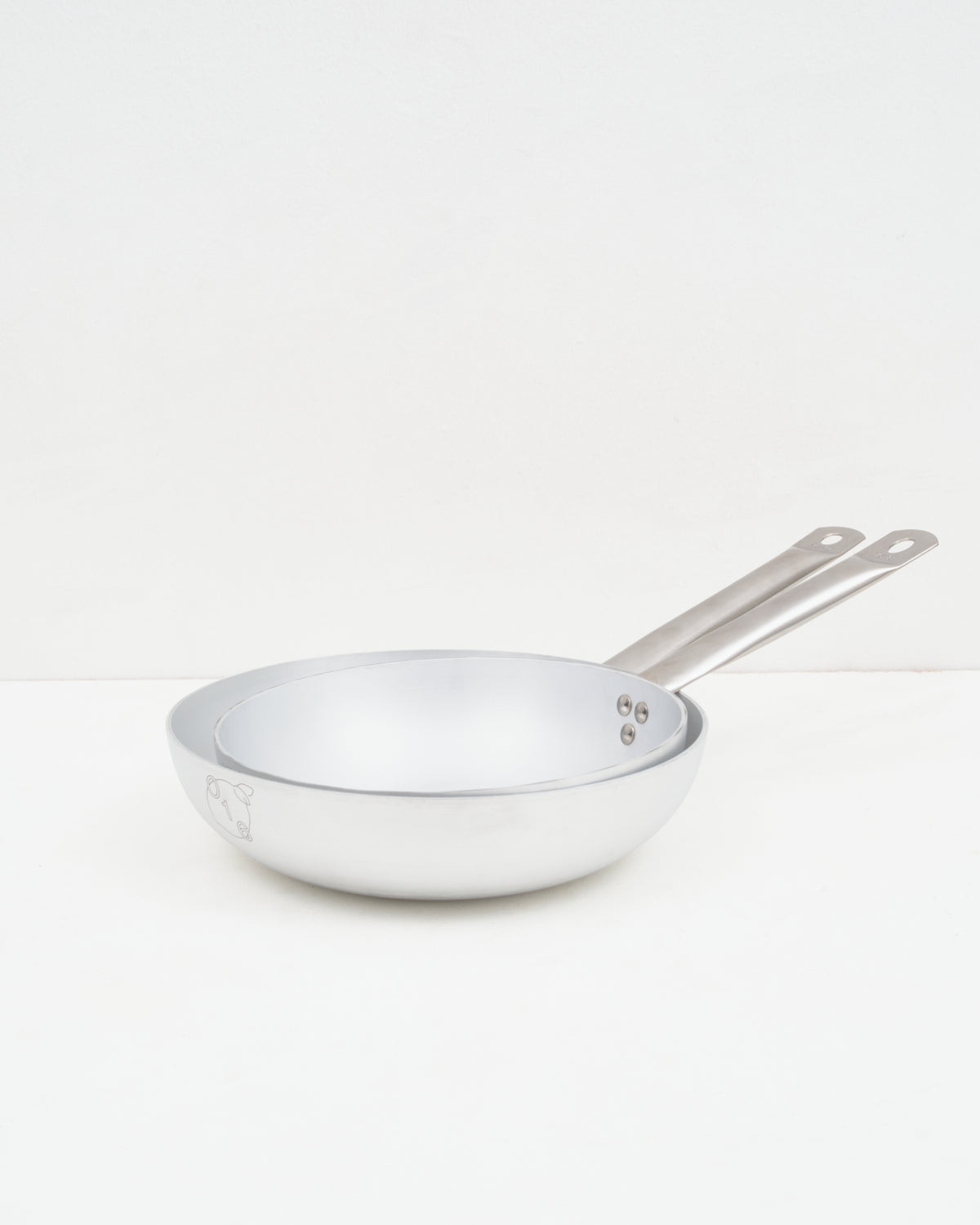 O16 Padella stegepander i to størrelser i aluminium med lange stålhåndtag — stablet forfra, Osteria 16 | O16 Padella frying pans in two sizes in aluminium with long steel handles — stacked front view, Osteria 16