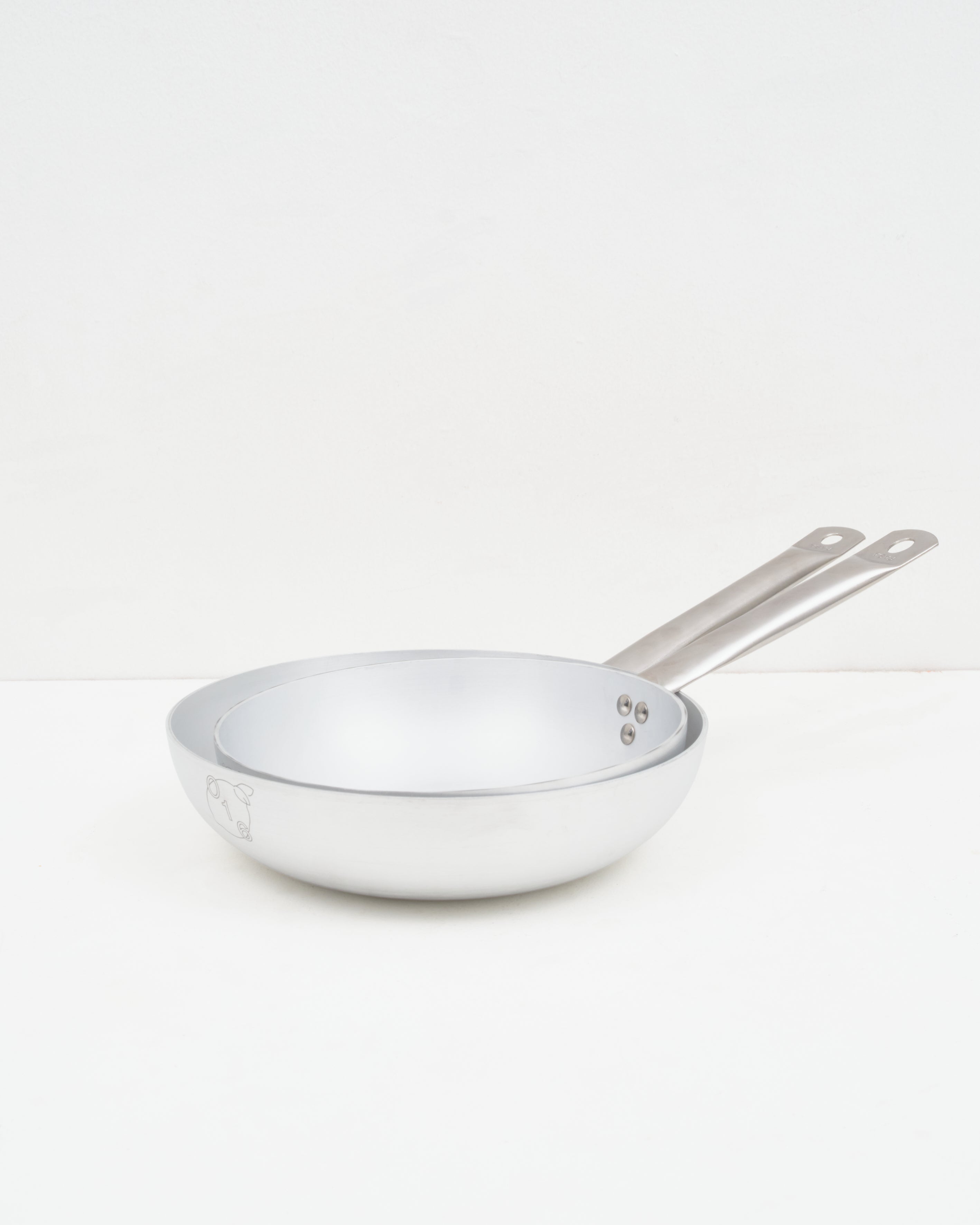 Studio: O16 Padella stegepander i to størrelser i aluminium med lange stålhåndtag — stablet forfra, Osteria 16 | O16 Padella frying pans in two sizes in aluminium with long steel handles — stacked front view, Osteria 16