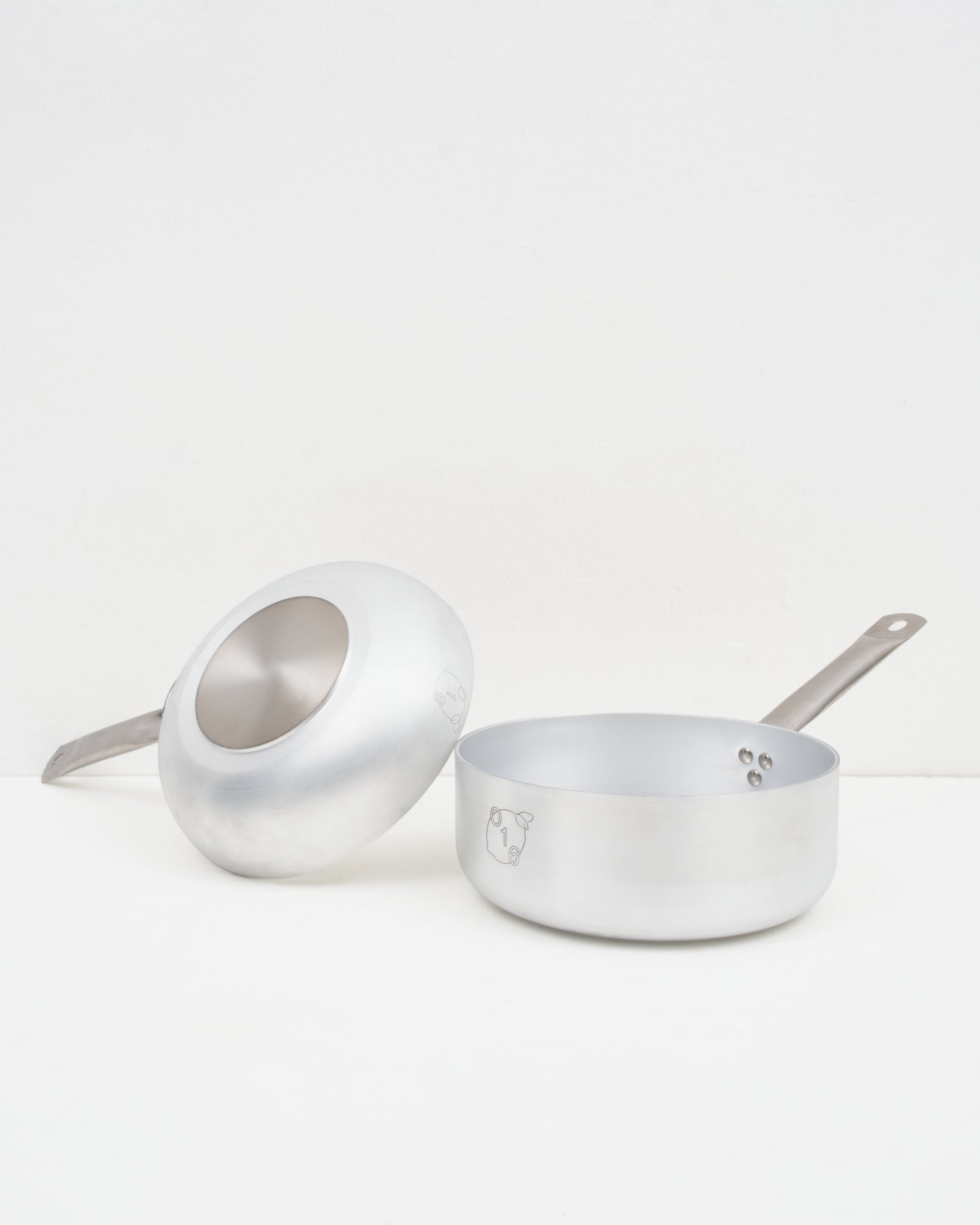 Studio: O16 lille aluminiumskokkesaet med vendt stegepande og kasserolle fra Osteria 16 — studiebillede der viser bund og form | O16 small aluminium cookware bundle with an upturned frying pan and saucepan by Osteria 16 — studio shot showing base and form