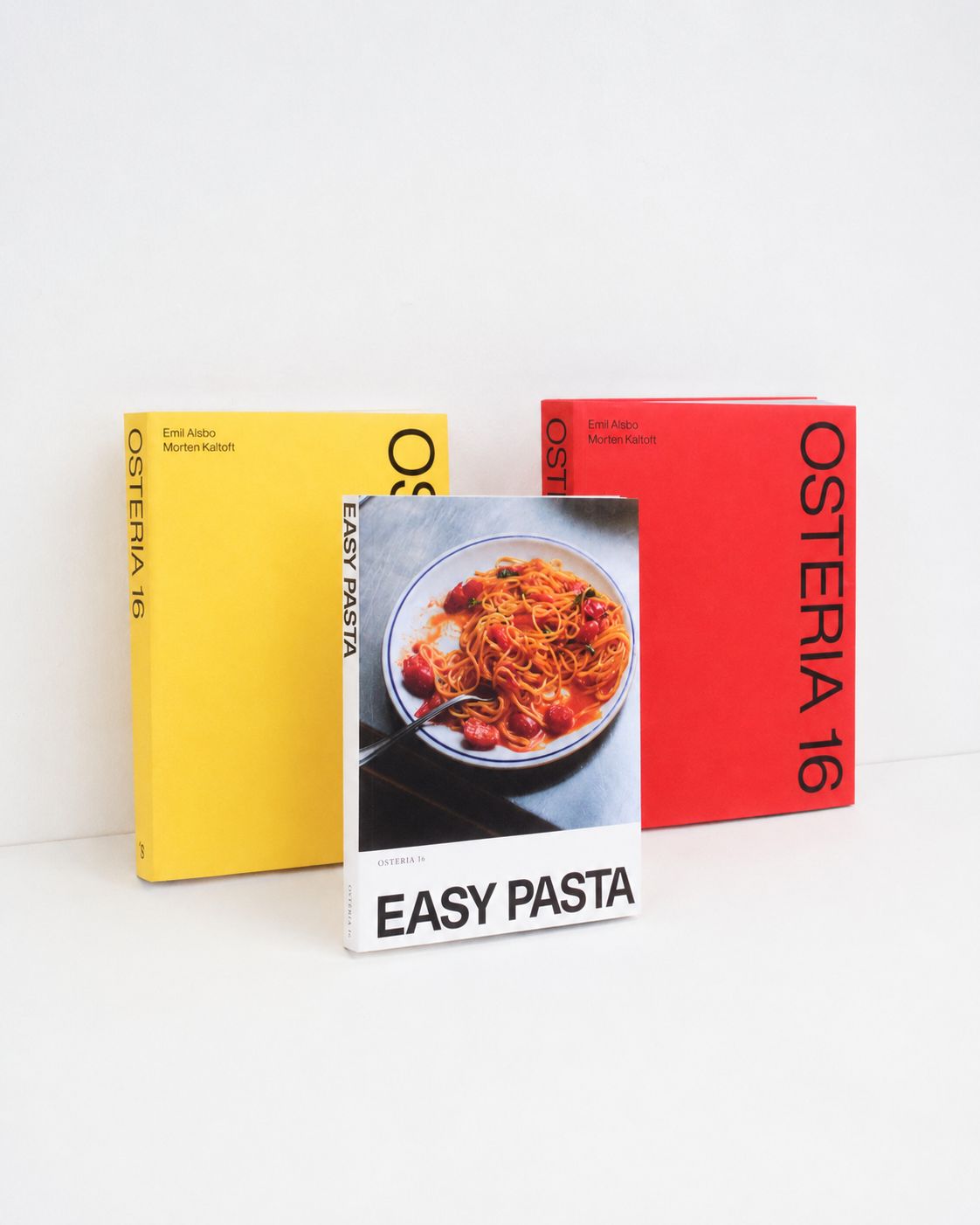 Studio: Osteria 16 kogebøger i gul og rød med "Easy Pasta" foran på hvid baggrund — studieoptagelse | Osteria 16 cookbooks in yellow and red with "Easy Pasta" in front on white — studio shot
