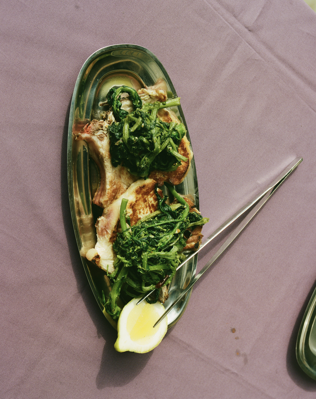 In-use: Grillede koteletter og grønne broccolini på et ovalt Vassoio serveringsfad i stål med citron og O16 Pinze tang | Grilled chops and green broccoli rabe on an oval steel Vassoio serving platter with lemon and O16 Pinze tongs
