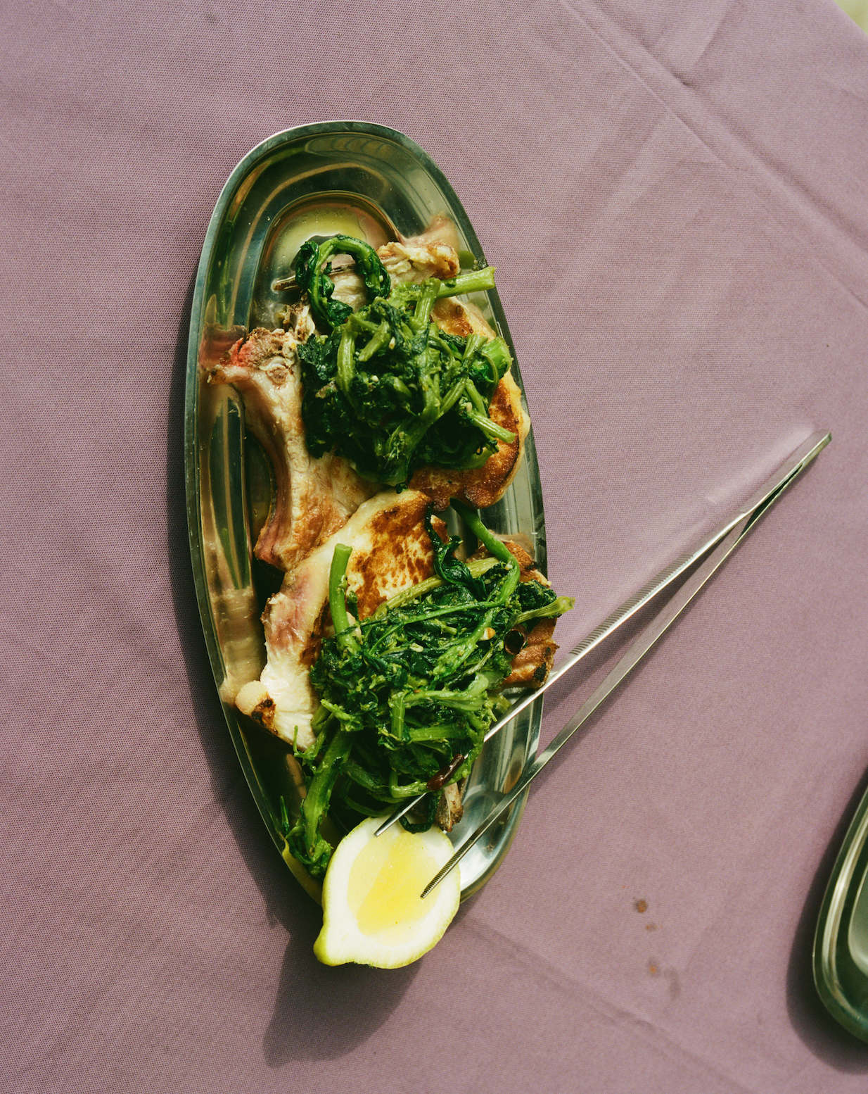 In-use: Grillede koteletter og grønne broccolini på et ovalt Vassoio serveringsfad i stål med citron og O16 Pinze tang | Grilled chops and green broccoli rabe on an oval steel Vassoio serving platter with lemon and O16 Pinze tongs