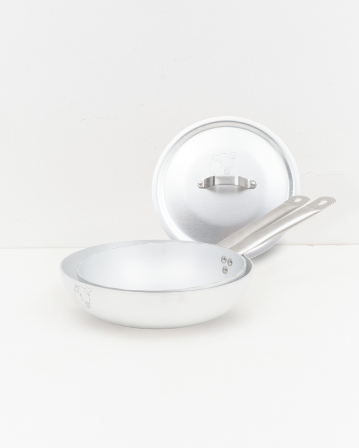 Studio: O16 Padella stegepande i aluminium med langt stålhåndtag og løst låg bagved — vinklet studiebillede, Osteria 16 | O16 Padella frying pan in aluminium with long steel handle and lid behind — angled studio shot, Osteria 16