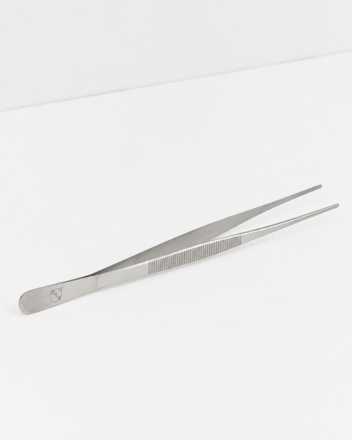 Studio: O16 Pinze køkkentang i rustfrit stål i fuld længde med graveret citron-logo, studieshot på hvid | O16 Pinze stainless steel kitchen tongs shown full length with engraved lemon logo, studio shot on white