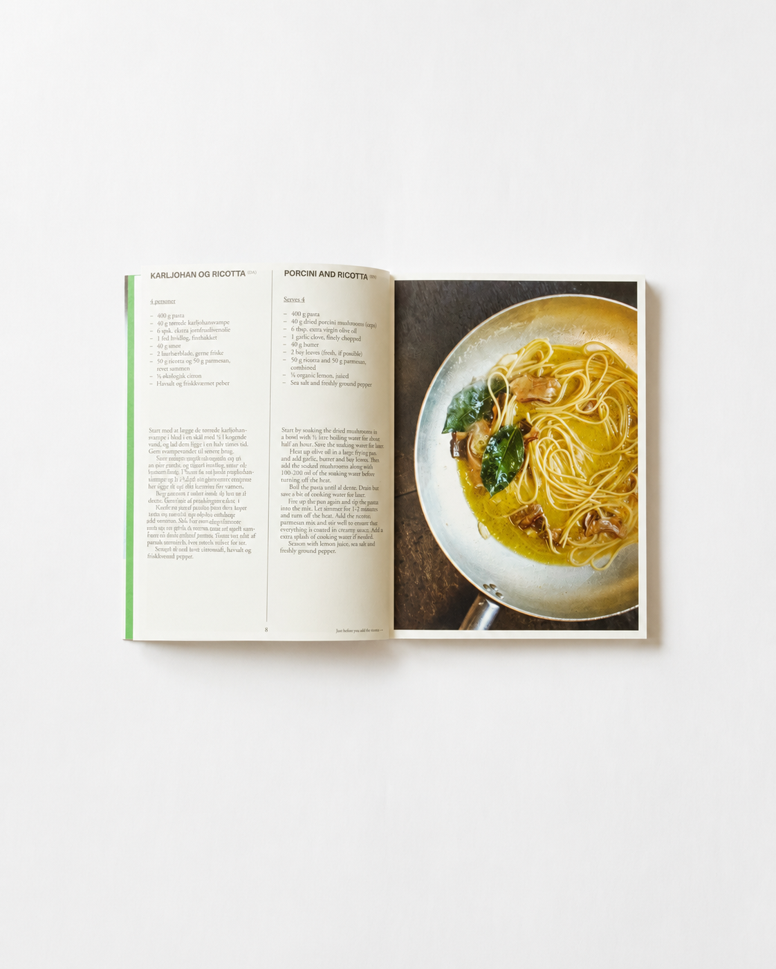 Opslag i O16 kogebog med Porcini and Ricotta, Karljohan og ricotta, og foto af pasta i pande. | Spread in the O16 cookbook showing the Porcini and Ricotta recipe with a photo of pasta in a frying pan.