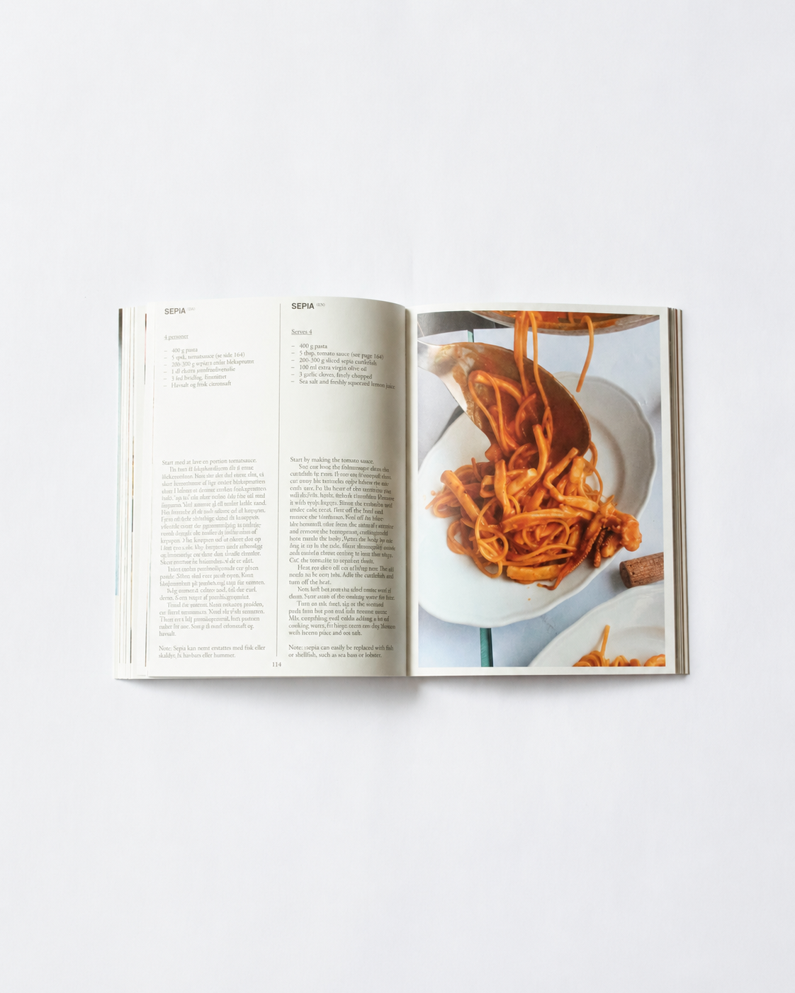 !Pages: Opslag i O16 kogebog med Sepia-opskriften, blæksprutte-pasta, og foto af tomatrød pasta på tallerken. | Spread in the O16 cookbook showing the Sepia cuttlefish-pasta recipe with a photo of tomato-red pasta on a plate.