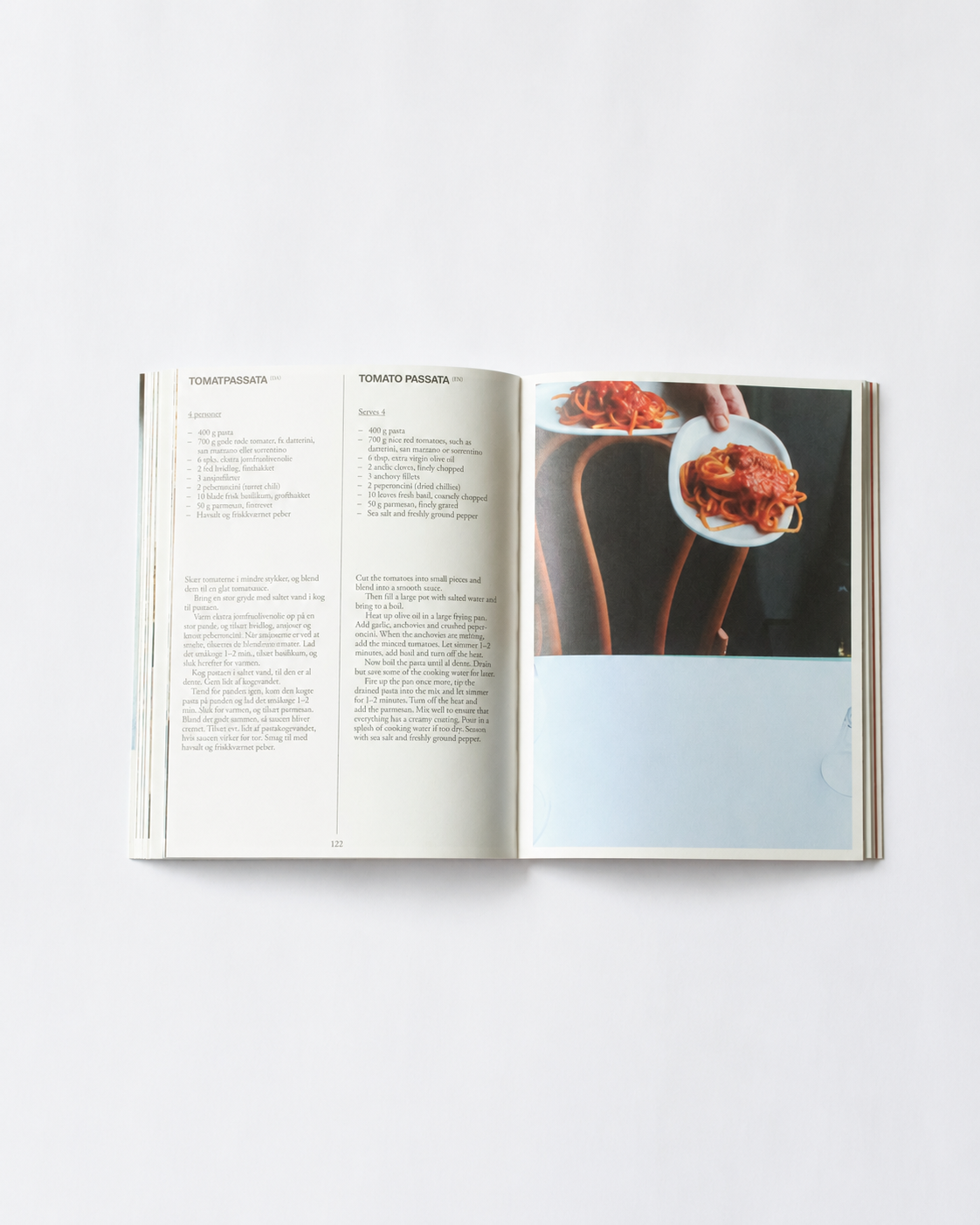 Opslag i O16 kogebog med Tomatpassata, Tomato Passata, og foto af hånd der holder tomat-spaghetti. | Spread in the O16 cookbook showing the Tomato Passata recipe with a photo of a hand holding tomato spaghetti.