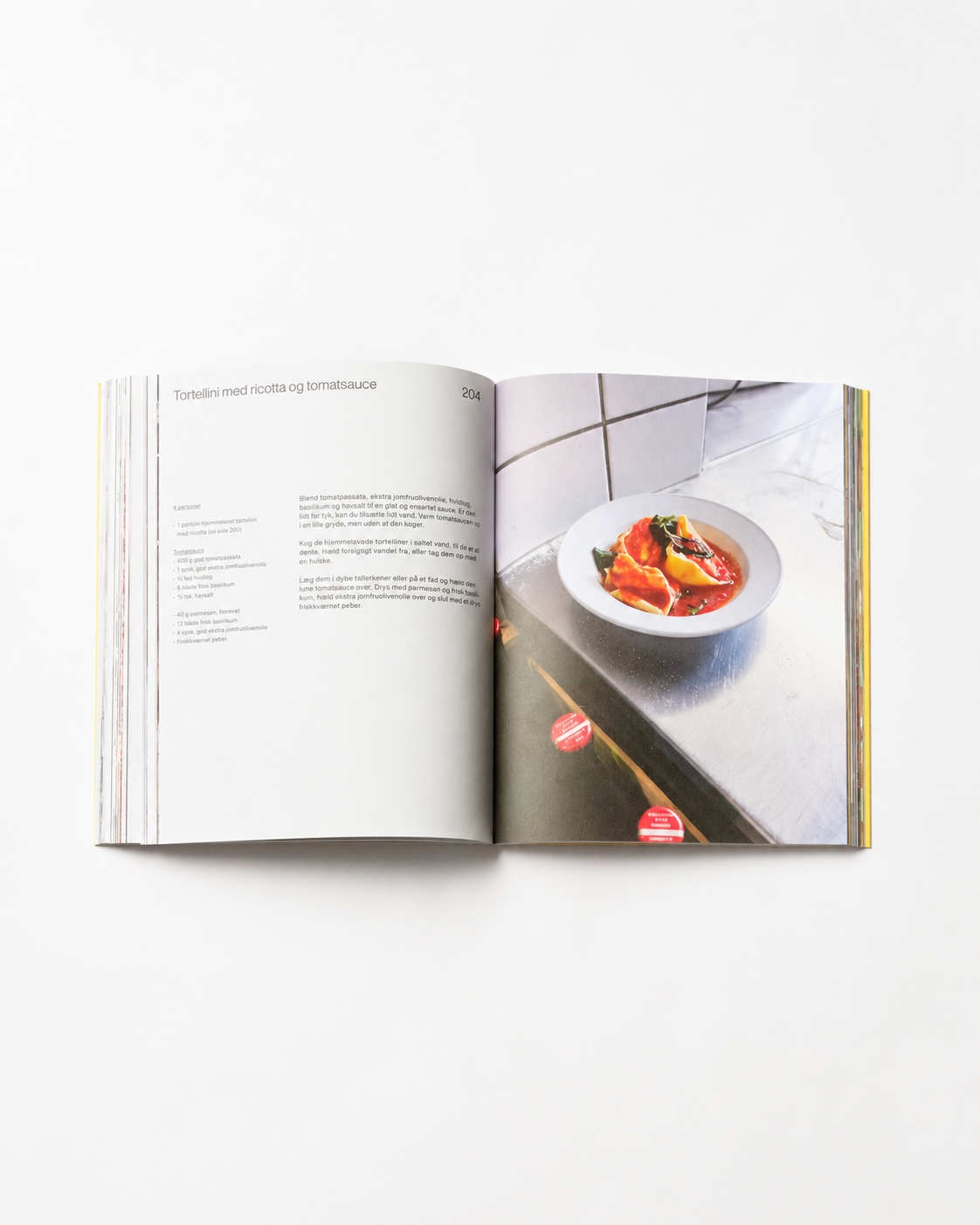 !Pages: Opslag i O16 kogebog med Tortellini med ricotta og tomatsauce og foto af tortellini i tomatsauce. | Spread in the O16 cookbook showing the Tortellini with ricotta and tomato sauce recipe, tortellini in tomato sauce.