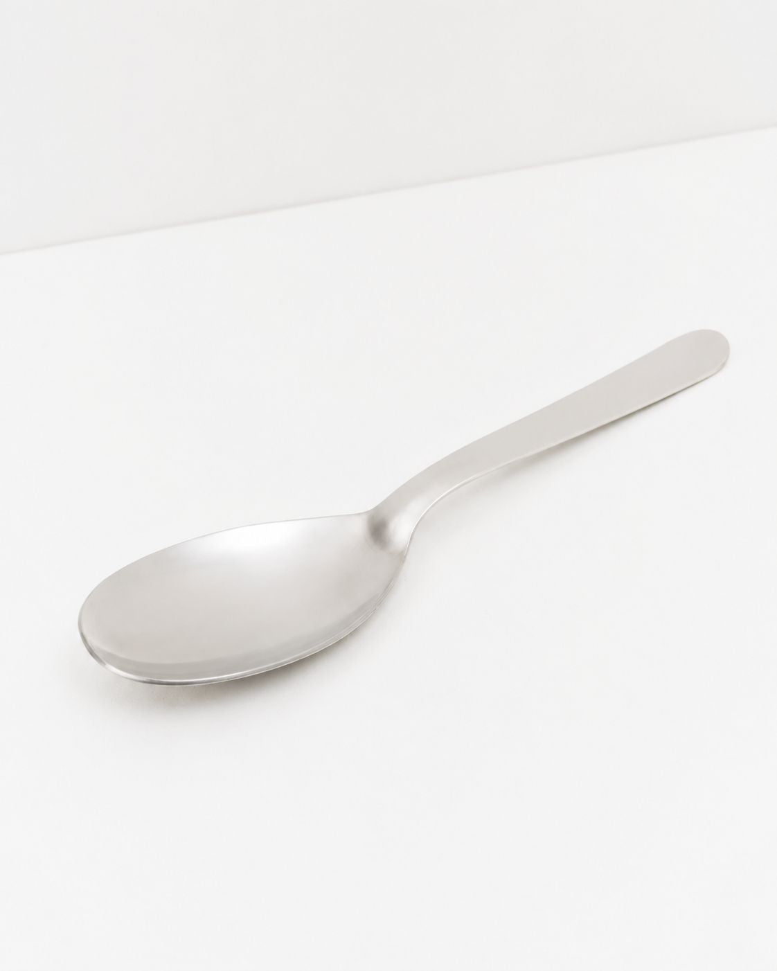 Studio: O16 serveringsske i rustfrit stål set fra siden, studiefoto på hvid baggrund | O16 stainless-steel serving spoon shown from the side, studio shot on a white background