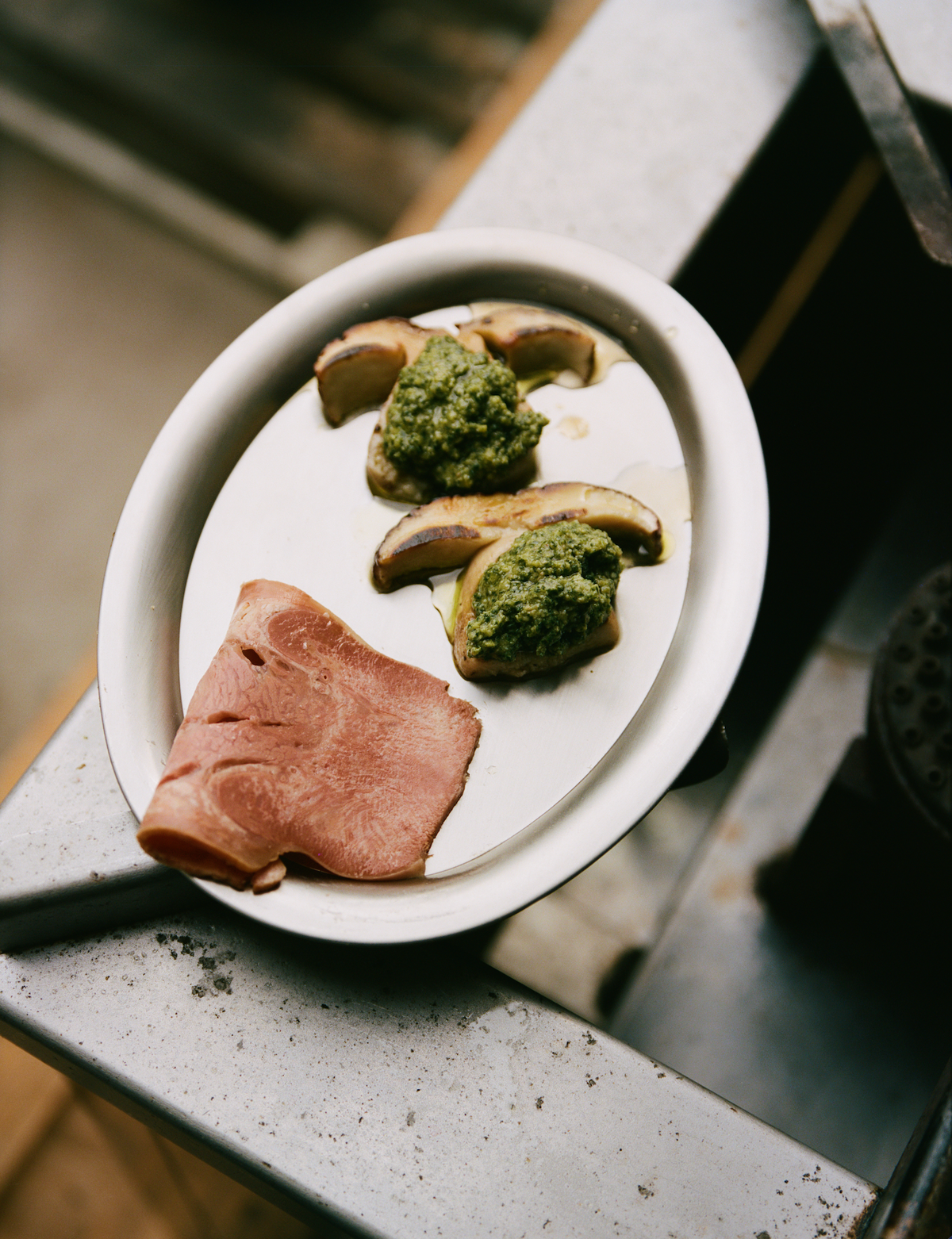 O16 Vassoio 1 lille ovalt fad med koldskåret skinke og grillede figner med pesto på rustikt underlag — lifestyle | O16 Vassoio 1 small oval dish with cold-cut ham and grilled figs with pesto on a rustic surface — lifestyle shot