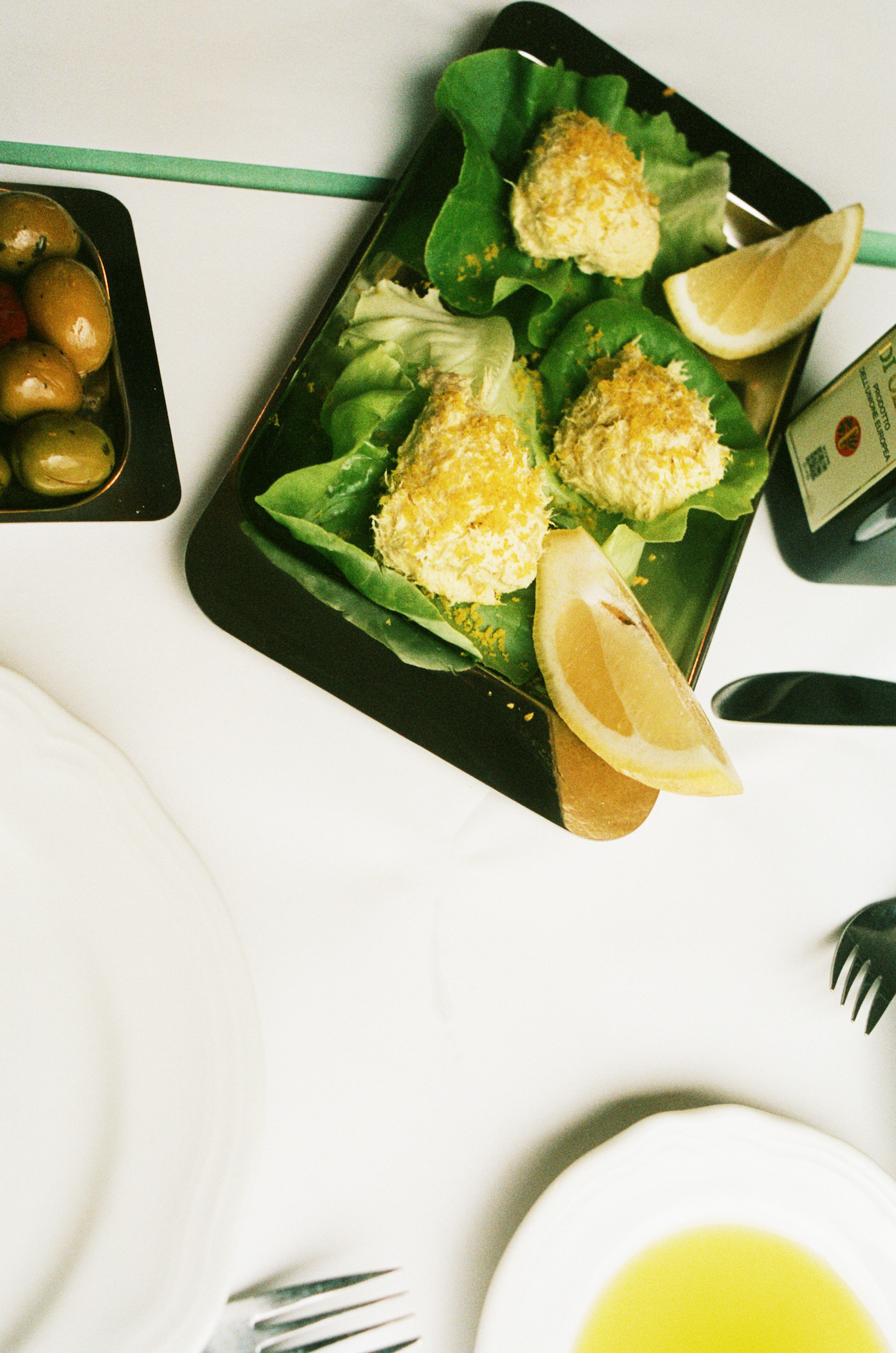 In-use: O16 Vassoio 4 mørkt rektangulært fad med sprøde arancini på salat og citron, oliven ved siden — lifestyle | O16 Vassoio 4 dark rectangular tray with crisp arancini on lettuce and lemon, olives alongside — lifestyle shot