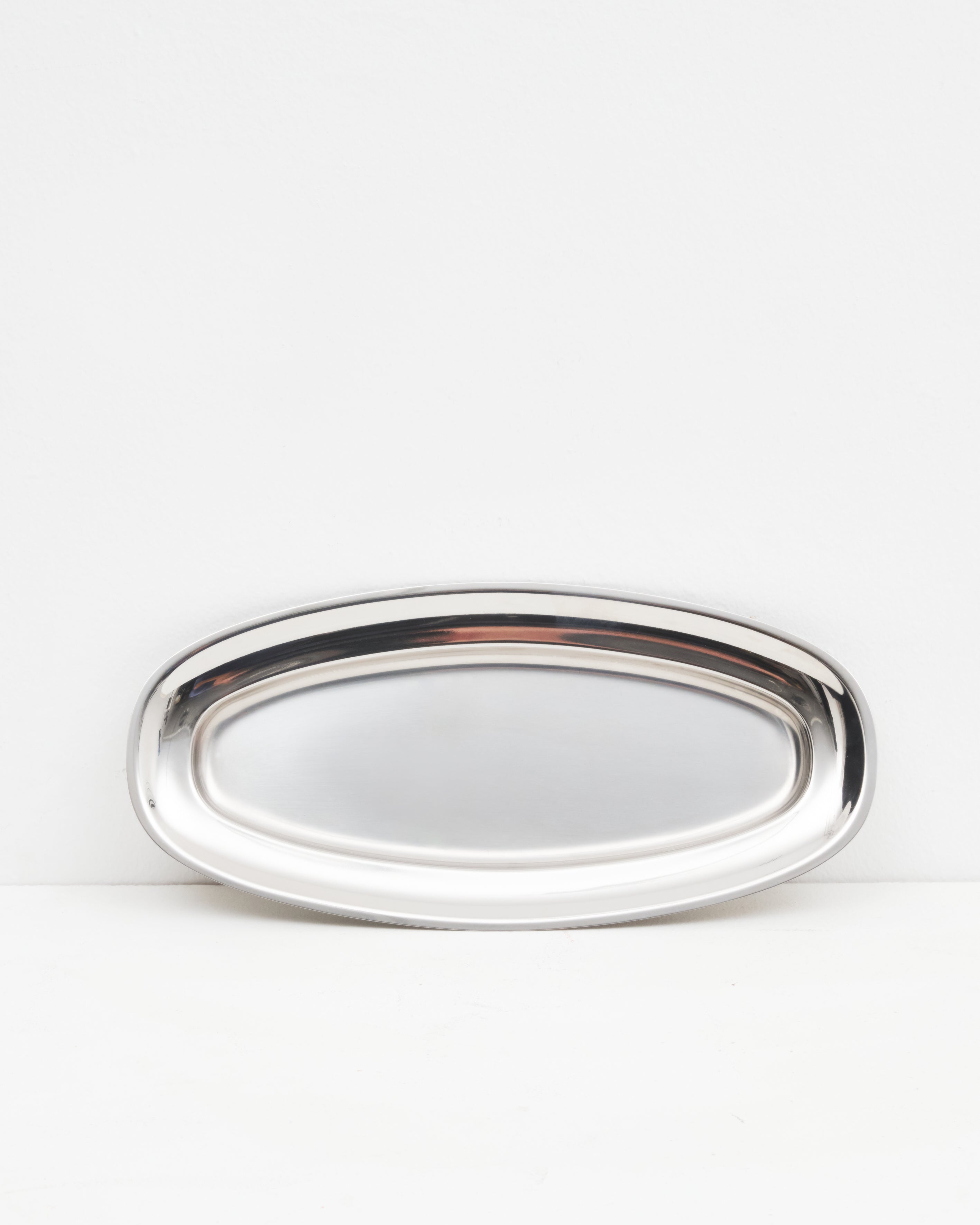 Studio: O16 Vassoio ovalt serveringsfad i blankt rustfrit stål, mellemstørrelse — hero-studiebillede på hvid | O16 Vassoio medium oval serving plate in polished stainless steel — hero studio shot on white
