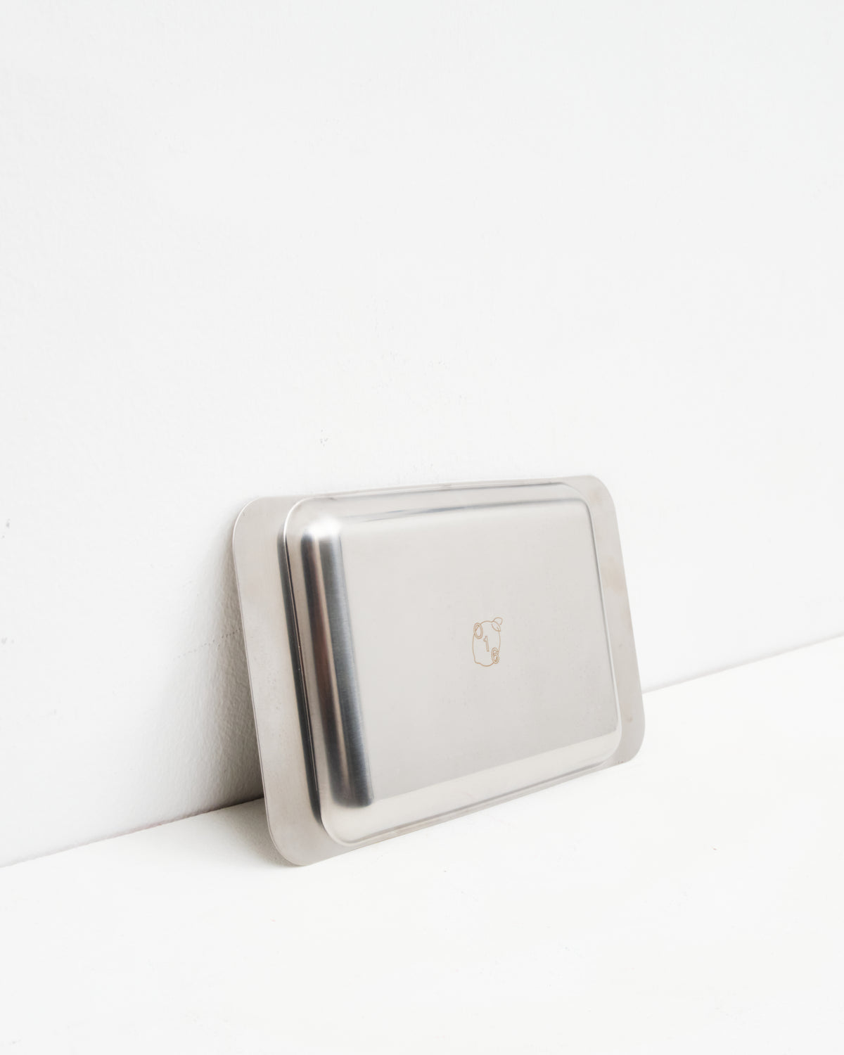 O16 Osteria 16 Vassoio 4 rektangulært serveringsfad i rustfrit stål lænet mod væg med indgraveret O16-logo, detaljebillede | O16 Osteria 16 Vassoio 4 rectangular stainless steel serving tray leaning against a wall with engraved O16 logo, detail shot