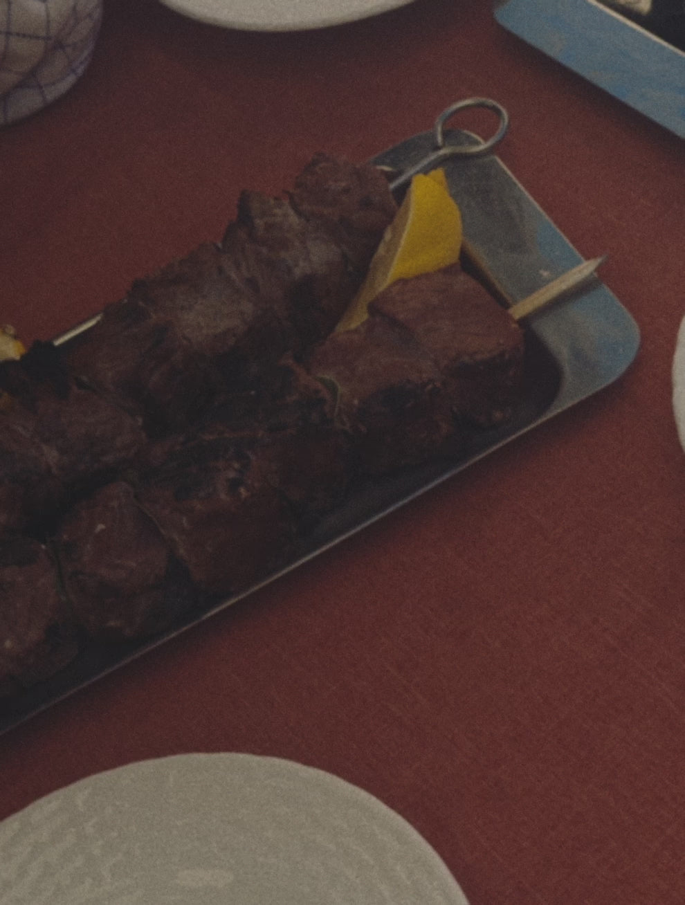 Motion: Videoklip fra Osteria 16 — en O16 Padella med skiveskåret stegt oksekød, grønt og friske krydderurter, tang og modne tomatskiver ved siden. | Osteria 16 motion clip — an O16 Padella of sliced seared beef, greens and fresh herbs with tongs, ripe tomato slices alongside.